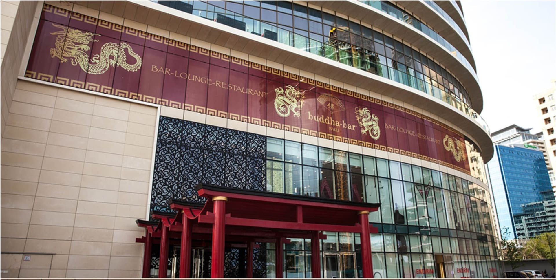 Binanın şüşə fasadında Buddha Bar yazılı bordo fon və qızılı əjdaha təsvirləri
