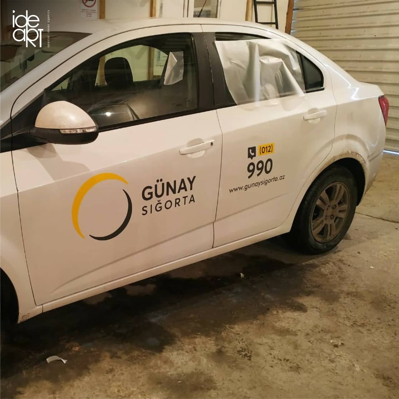 Günay Sığorta logo, phone number and website on white car doors.