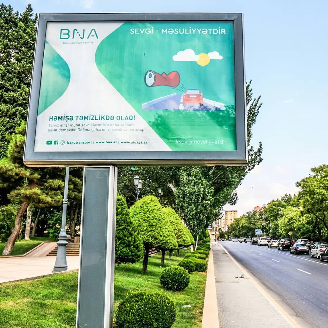 Yol kənarında təmizliyə çağıran, əzilmiş içki qabı təsvirli yaşıl BNA reklam lövhəsi